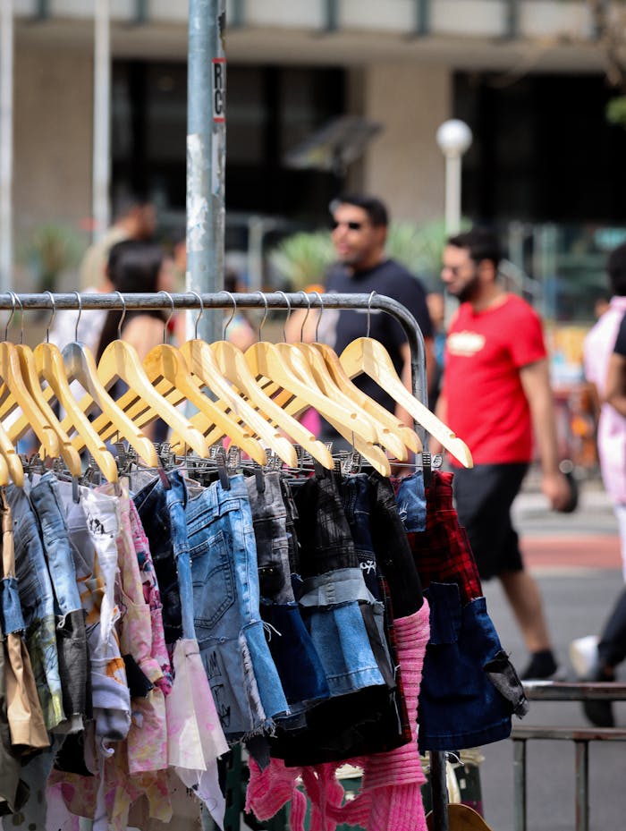 A vibrant outdoor market display featuring denim clothes with pedestrians behind.