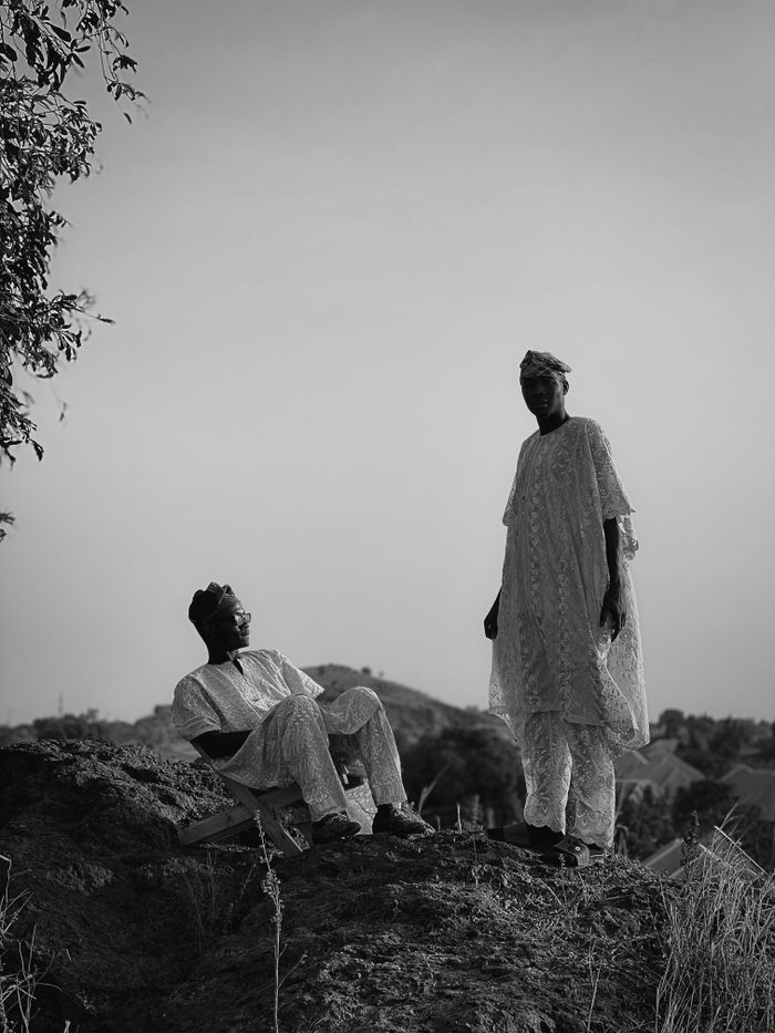 about-01 Black and white image of two men in traditional attire standing outdoors on a hill.
