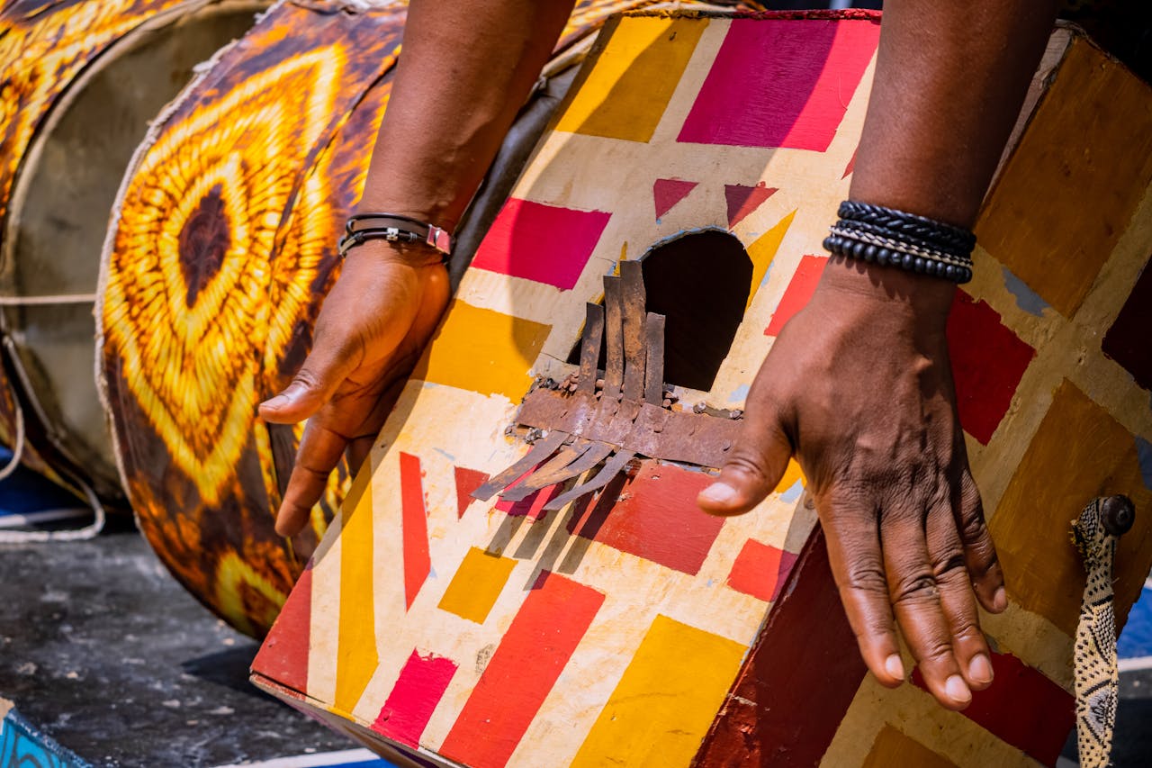 why-choose-us Close-up of hands playing a colorful, traditional drum with geometric patterns.