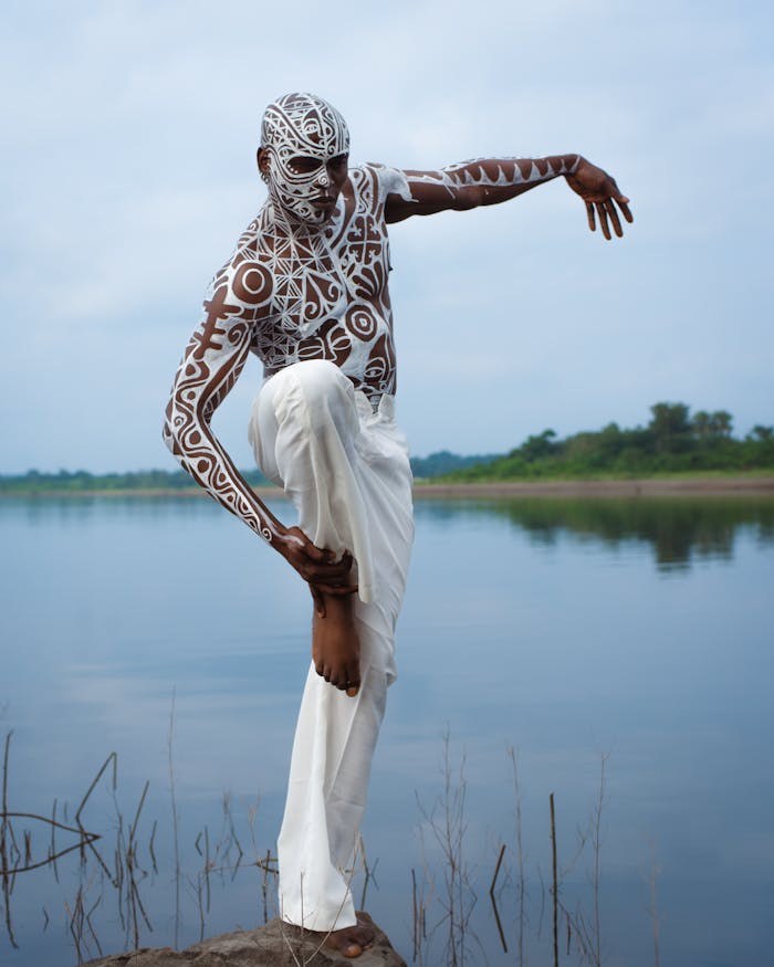 services-03 A person showcasing intricate body paint art by a serene Nigerian river environment.